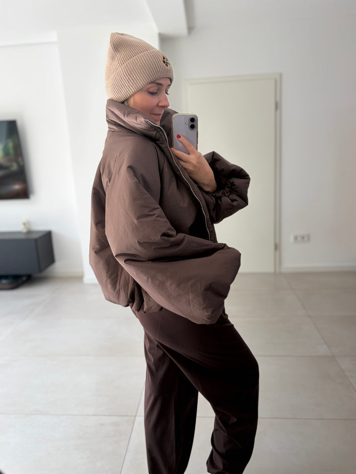 Taupefarbene Puffy Oversize-Ballonjacke am Model – seitliche Ganzkörperansicht der ballonartigen Silhouette