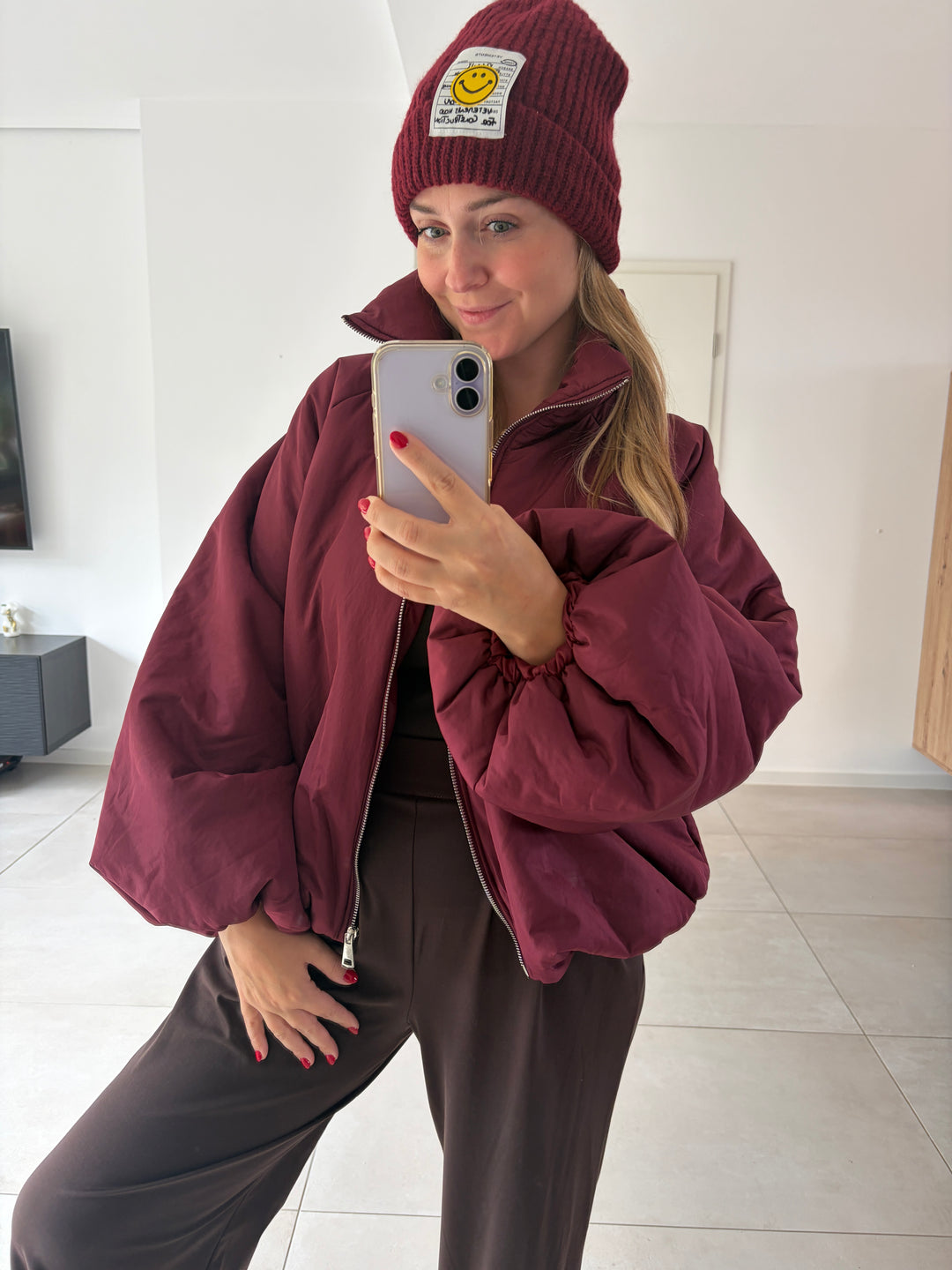 Model trägt bordeauxrote Puffy Oversize-Ballonjacke offen zur braunen Hose – Frontansicht mit voluminösen Ärmeln