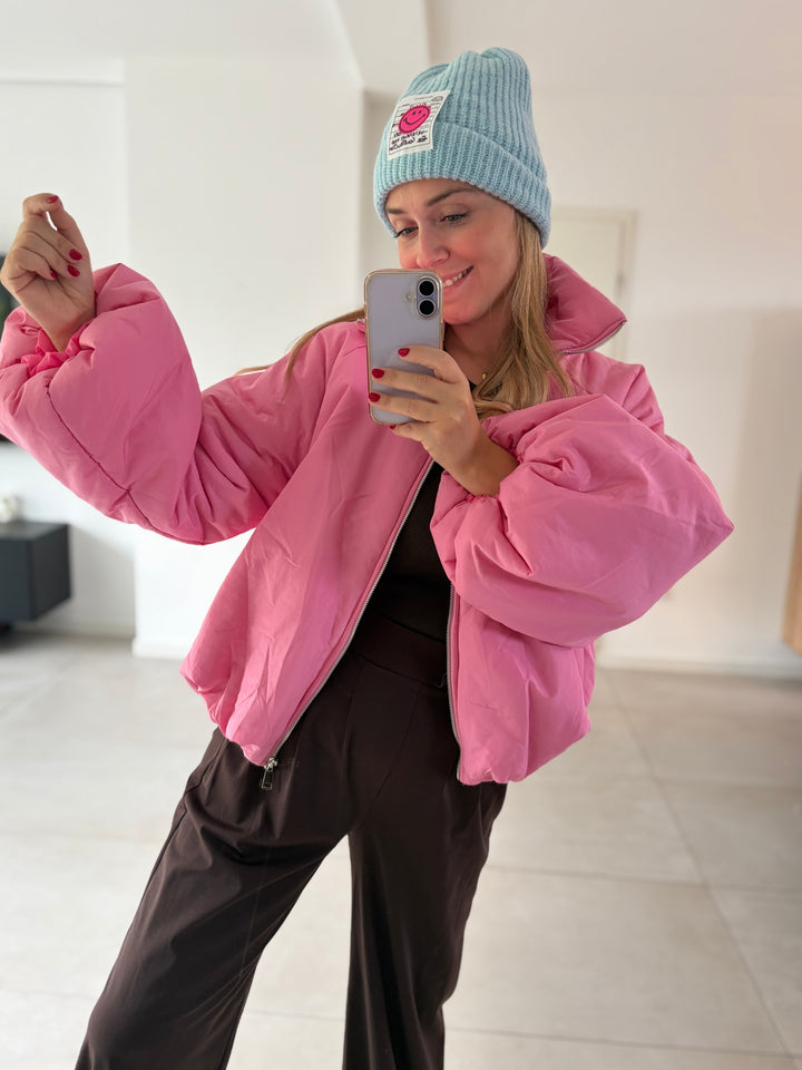 Model in rosa Puffy Oversize-Ballonjacke mit angehobenem Arm – voluminöser Ballonärmel im Fokus