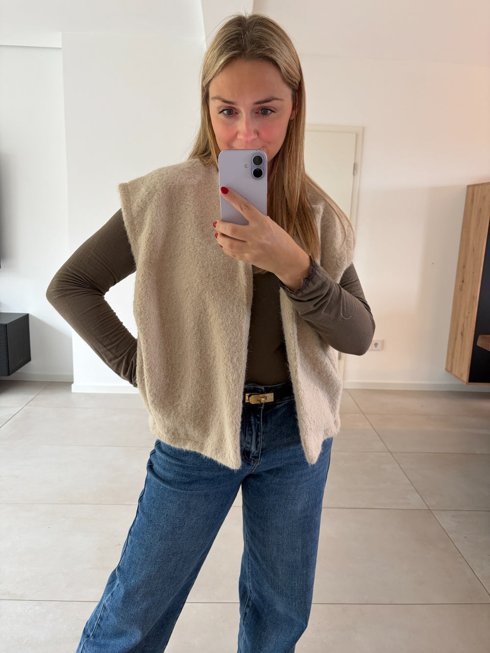 Flauschige Weste in Beige kombiniert mit braunem Longsleeve und blauer Jeans