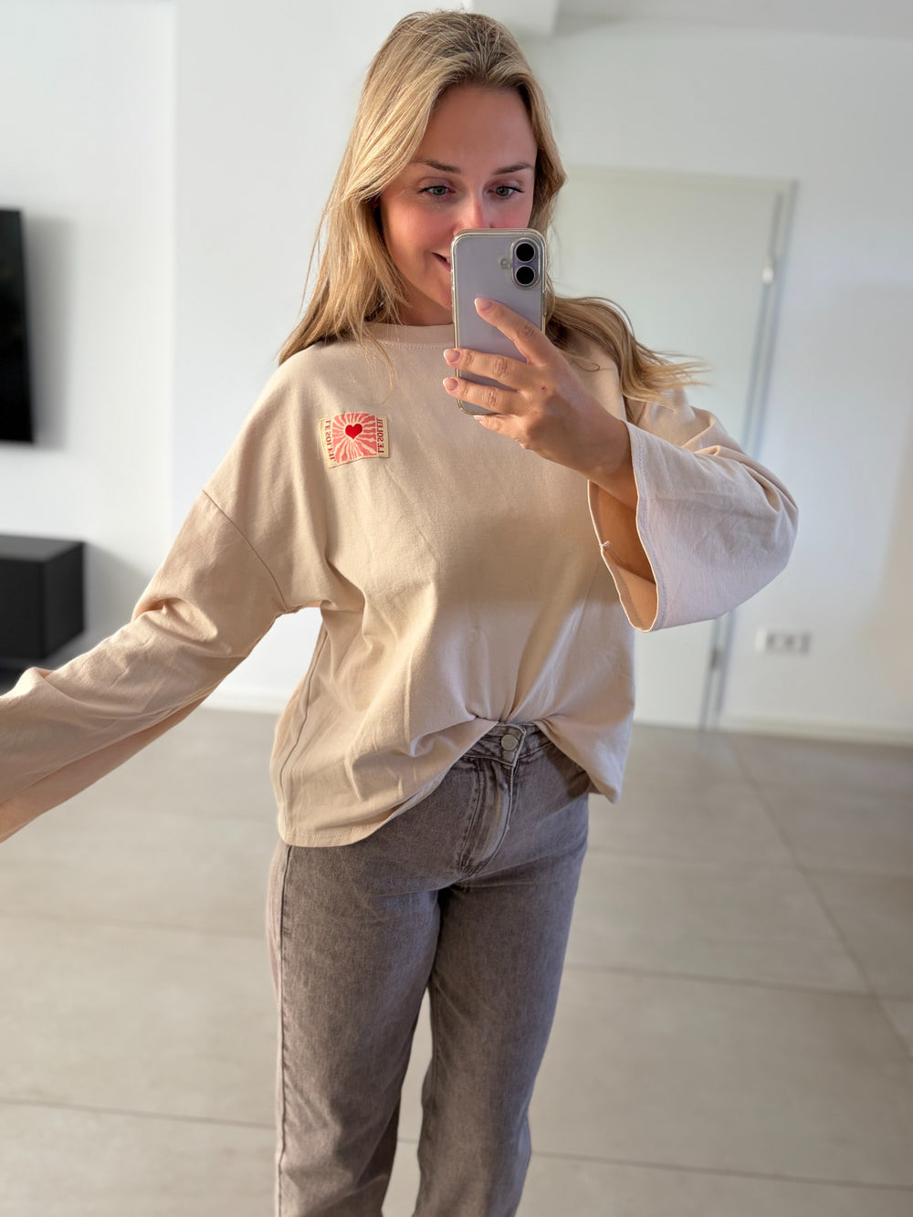 Beiges Oversize-Langarmshirt mit Herz-Patch – Ganzkörperansicht