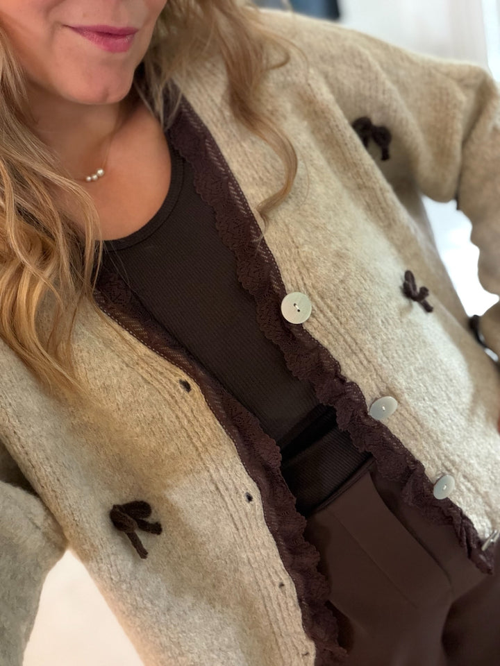 Beige Strickjacke mit braunen Schleifen und Knopfleiste – Detailansicht