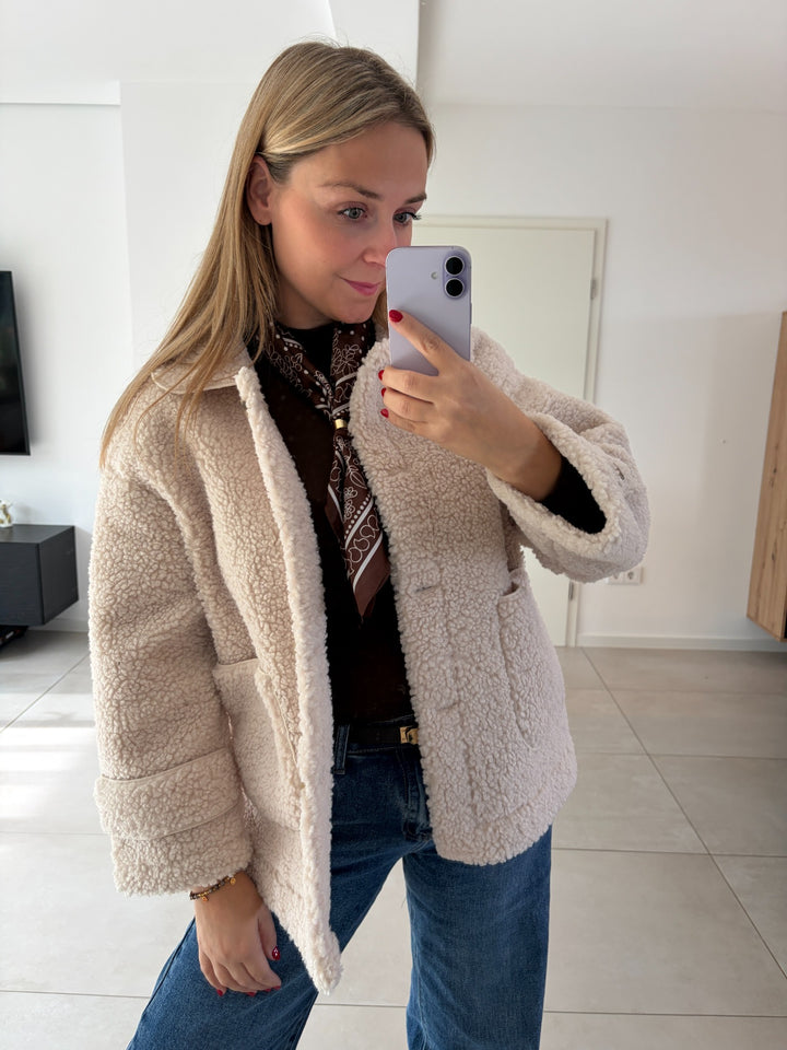 Teddy-Jacke in Creme offen getragen mit braunem Schal und Jeans