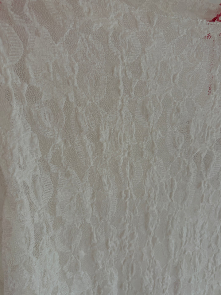Florale Spitze des weißen Langarmshirts im Detail
